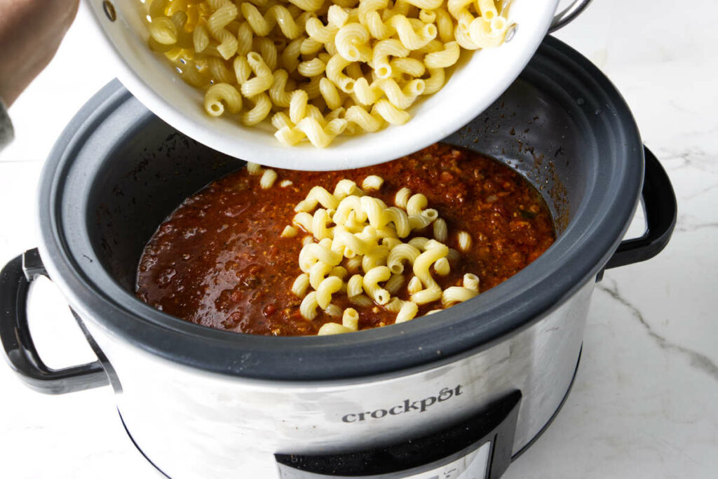 Stirring cooked pasta into the crockpot.