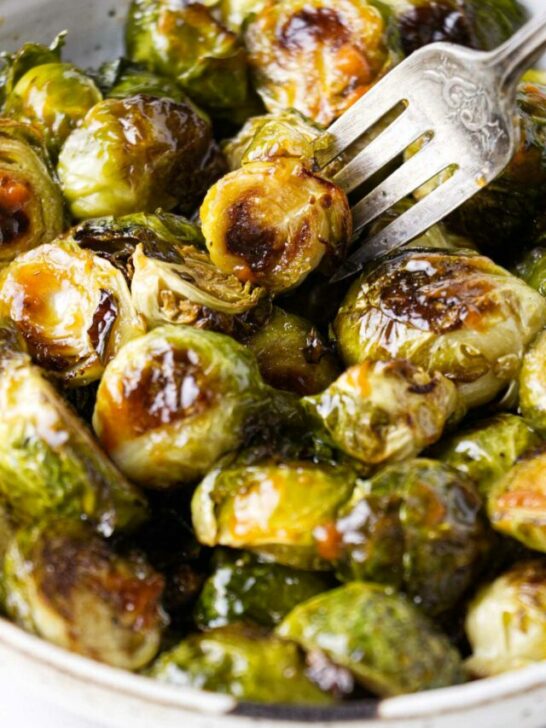 A fork in a dish with sriracha brussel sprouts.