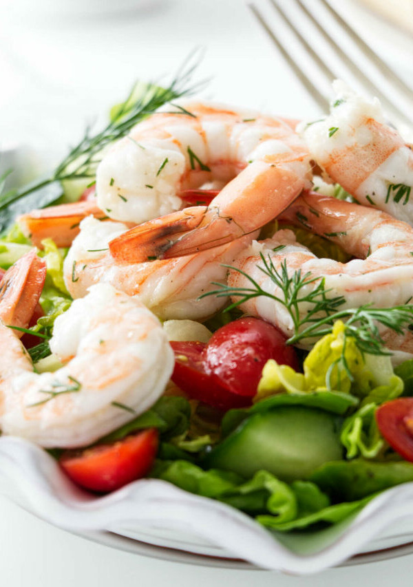 A green lettuce salad topped with shrimp.