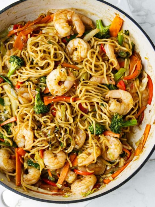 A large skillet of yakisoba with shrimp.