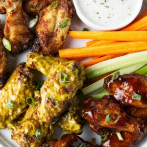 Traeger chicken wings on a serving plate with celery and carrot sticks.