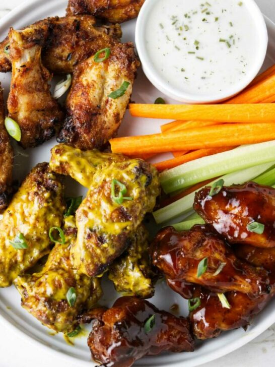 Traeger chicken wings on a serving plate with celery and carrot sticks.