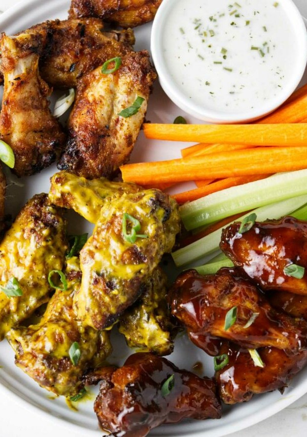 Traeger chicken wings on a serving plate with celery and carrot sticks.