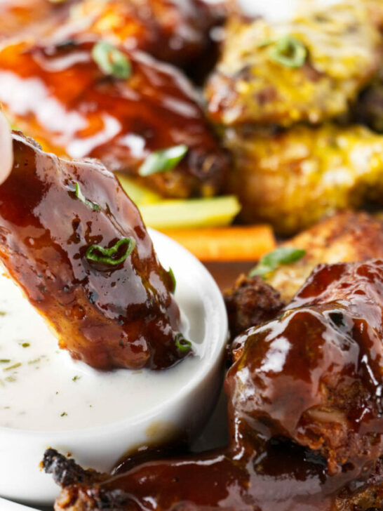 Dipping a chicken wing in ranch dressing.