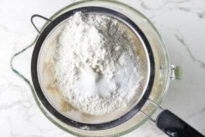 Sifting flour, salt, and baking soda over the mixing bowl.