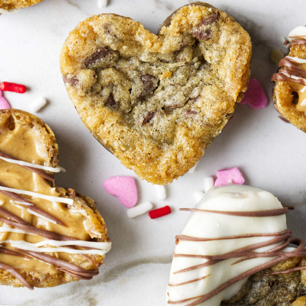 Heart shaped chocolate chip cookies on a plate with sprinkles.