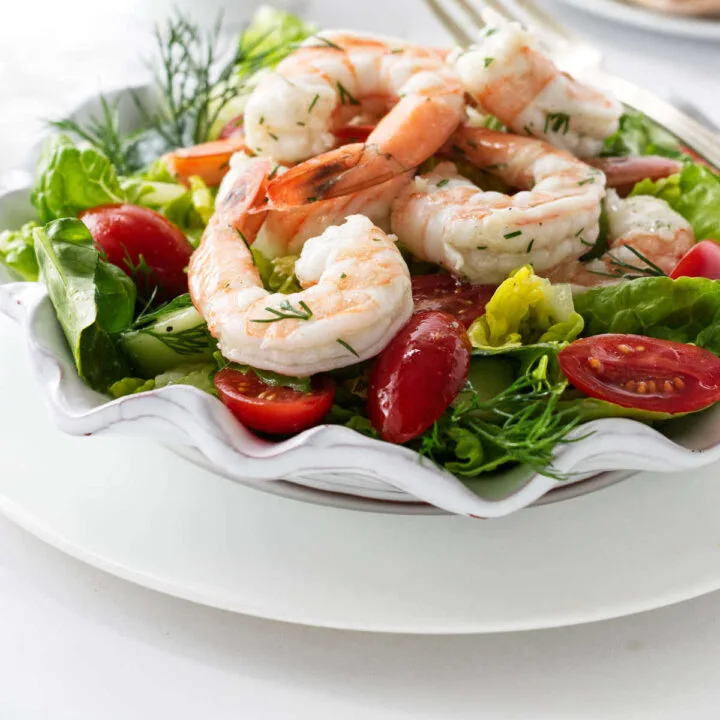 A lettuce salad with shrimp, tomatoes, and cucumbers.