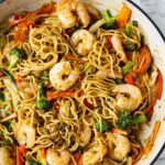 A large skillet filled with shrimp yakisoba.