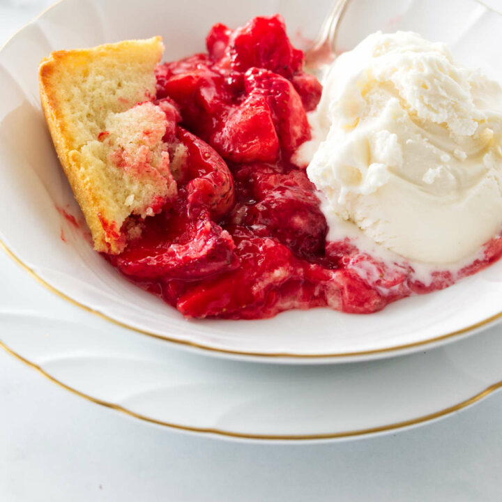 A serving of strawberry spoon cake in a dish with ice cream.