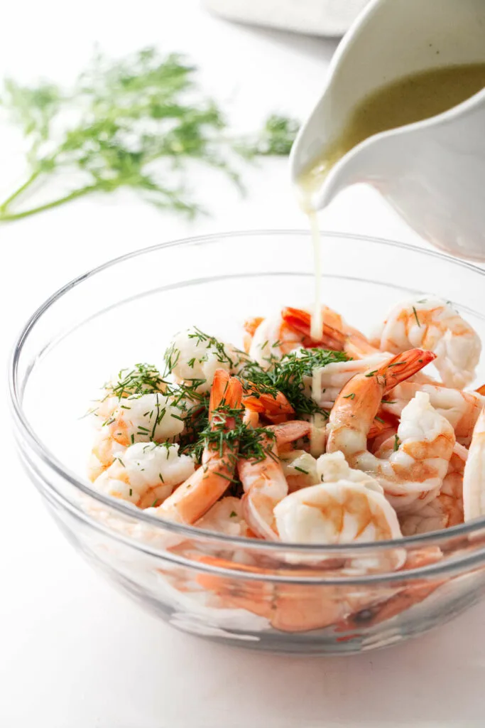 Mixing shrimp with herbs and salad dressing.