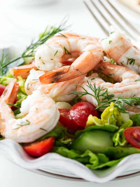 A green lettuce salad topped with shrimp.