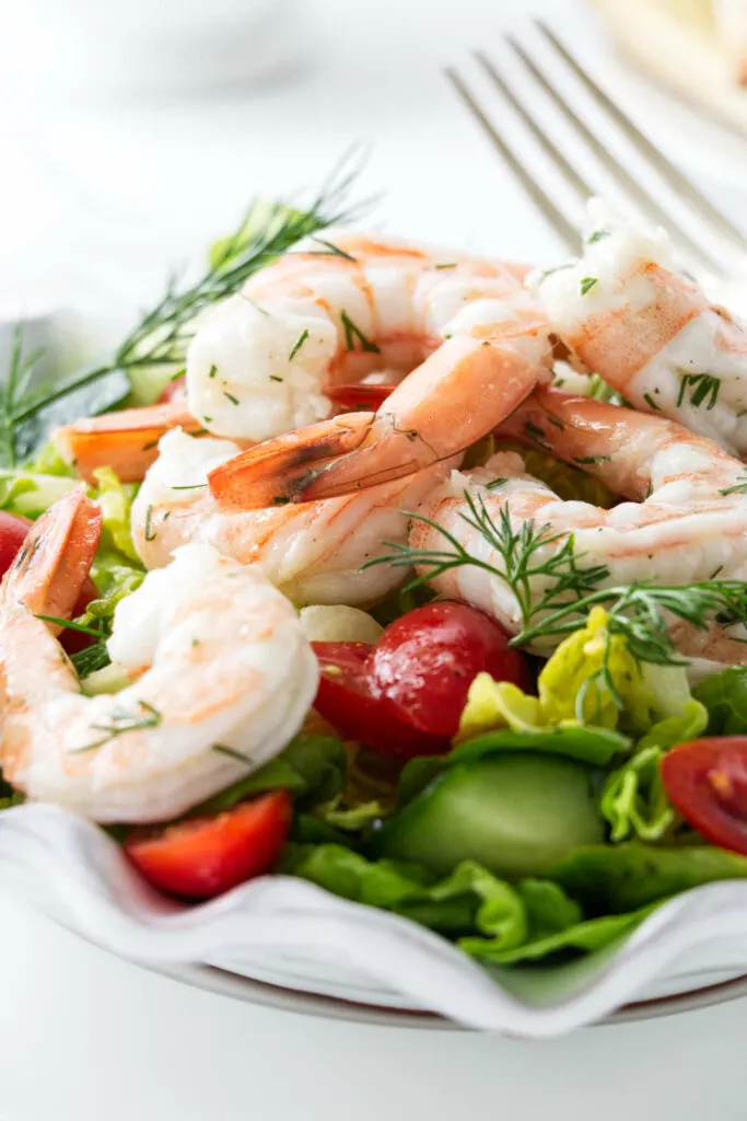 A green lettuce salad topped with shrimp.