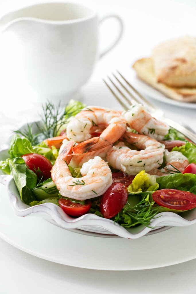 Lettuce salad topped with shrimp and tomatoes.