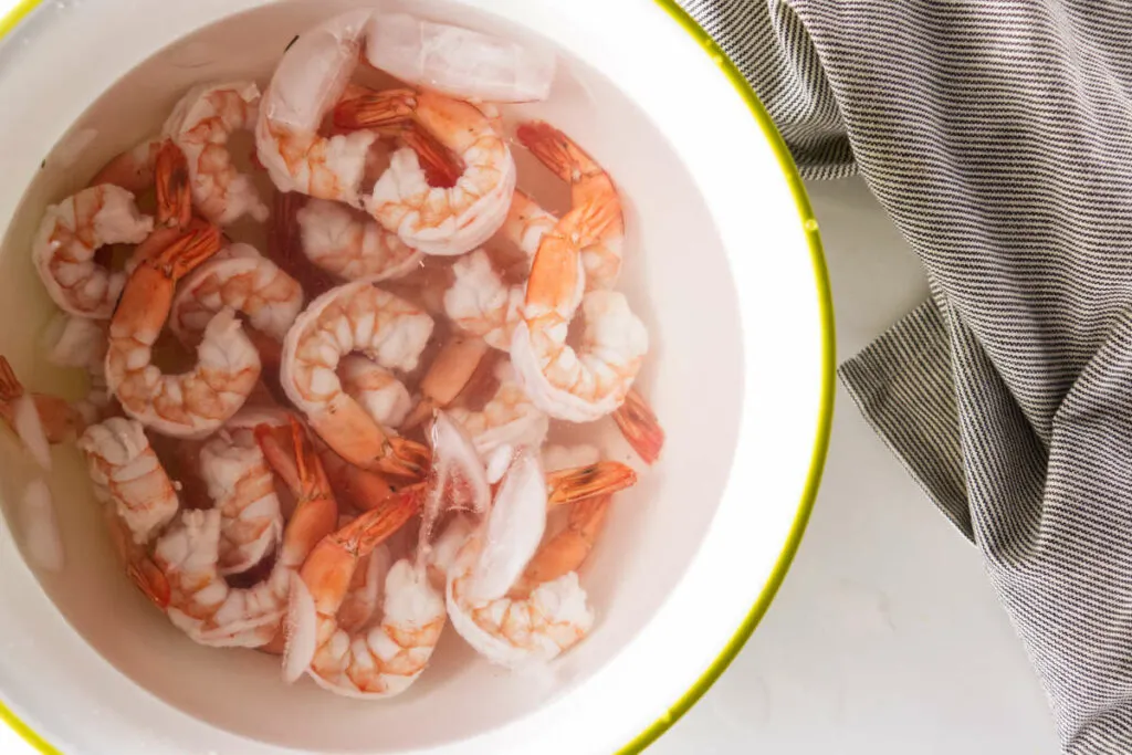 Shocking cooked shrimp in ice water to stop them from cooking.