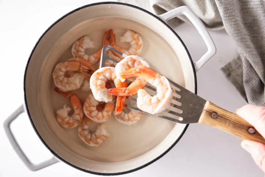 Removing shrimp from a pot of hot water.