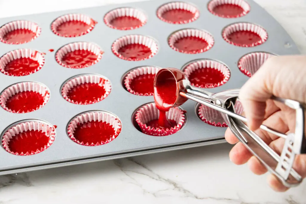 Pouring cake batter into mini muffin tins.