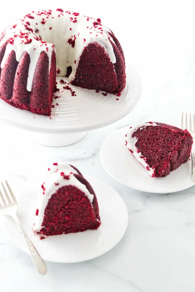 Two slices of red velvet bundt cake next to a cake on a platter.