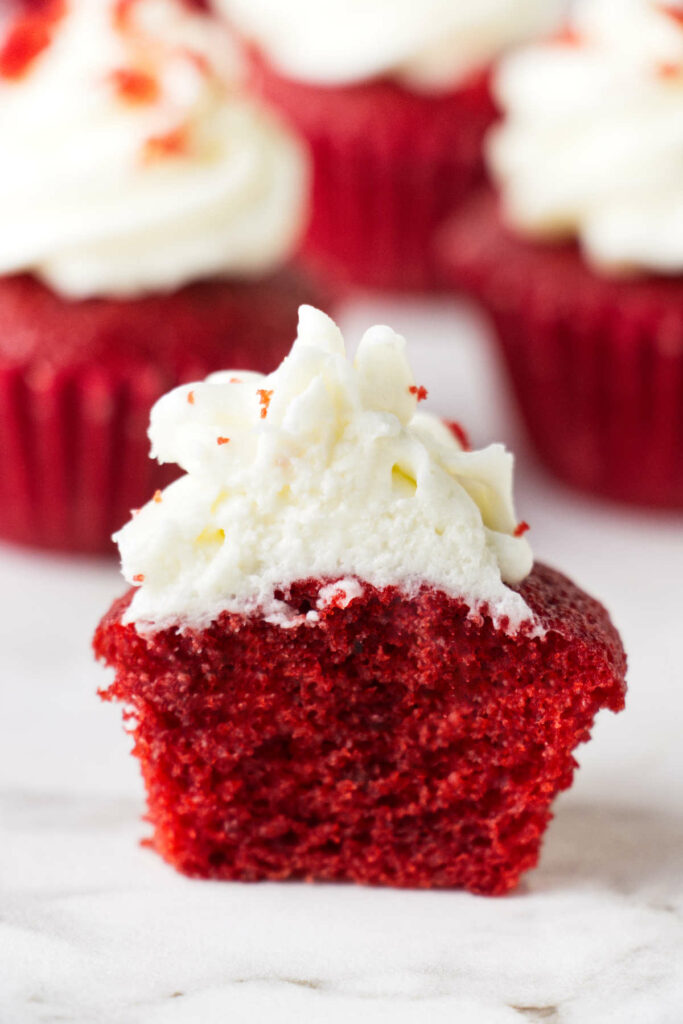 A mini cupcake sliced in half showing the red cake inside.