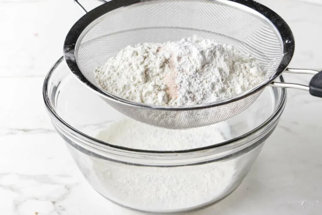 Sifting flour, salt, baking powder, and baking soda into a bowl.