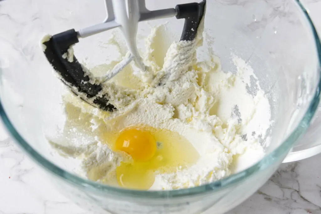 Mixing eggs into the batter.