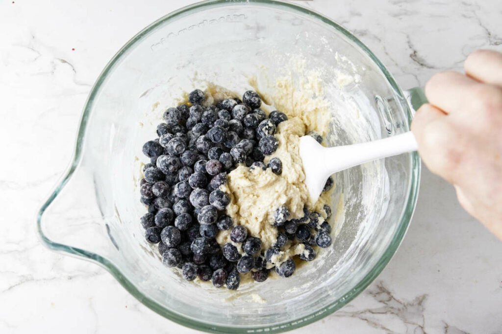 Folding blueberries into muffin batter.