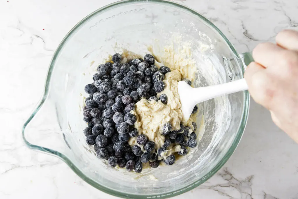 Folding blueberries into muffin batter.