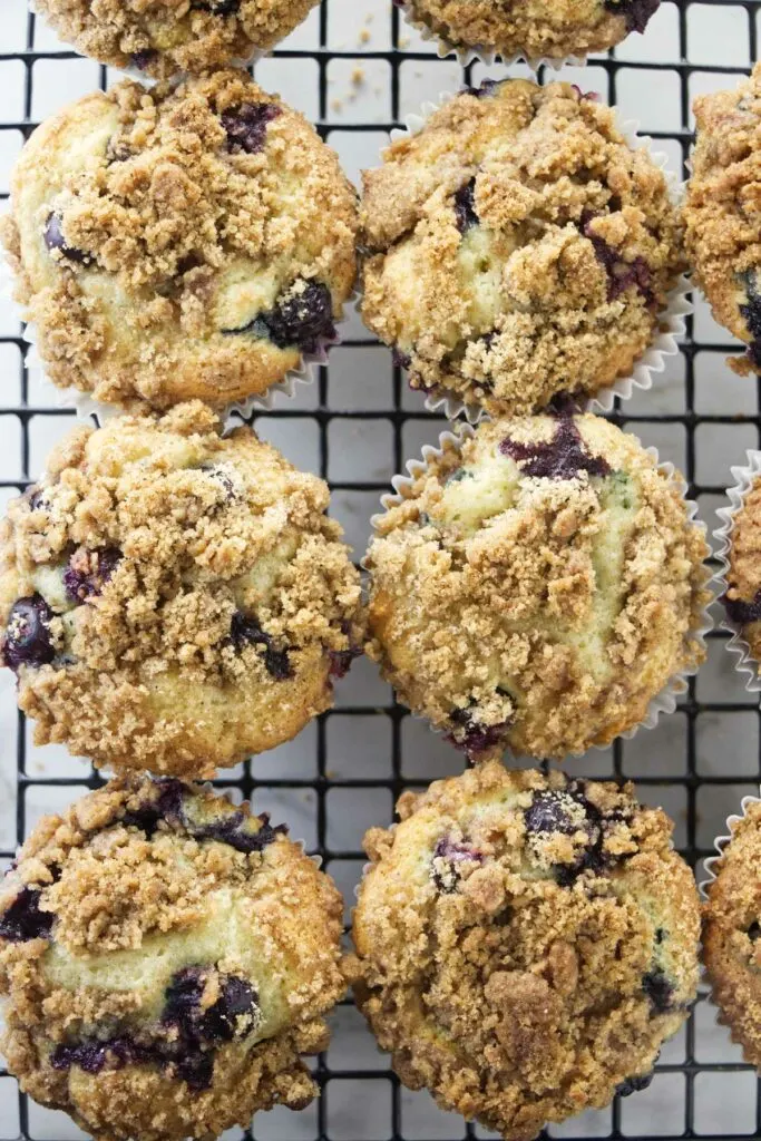 Streusel topped blueberry muffins cooling on a wire rack.