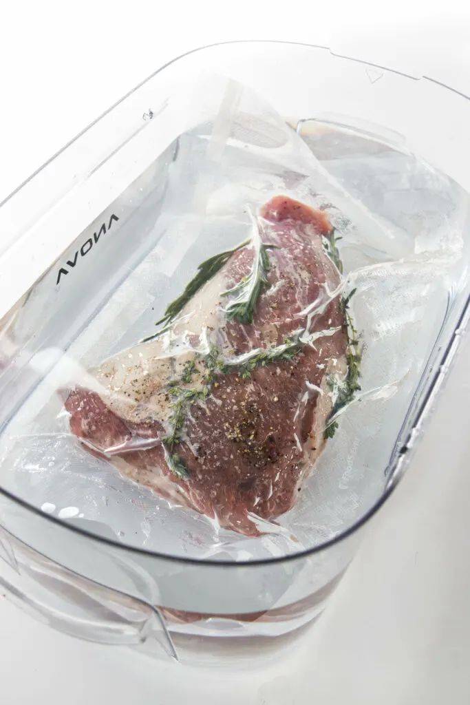 A tri tip sealed in a bag and cooking in a water bath for sous vide.