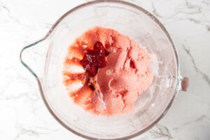 Mixing strawberry jam into buttercream mixture.