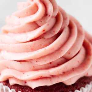 A cupcake topped with strawberry cream cheese frosting.