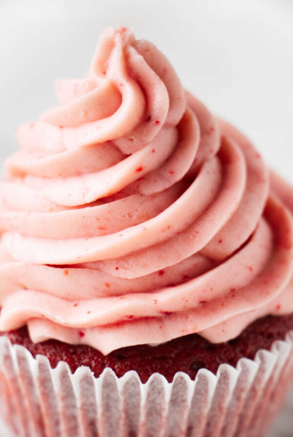 A cupcake topped with strawberry cream cheese frosting.