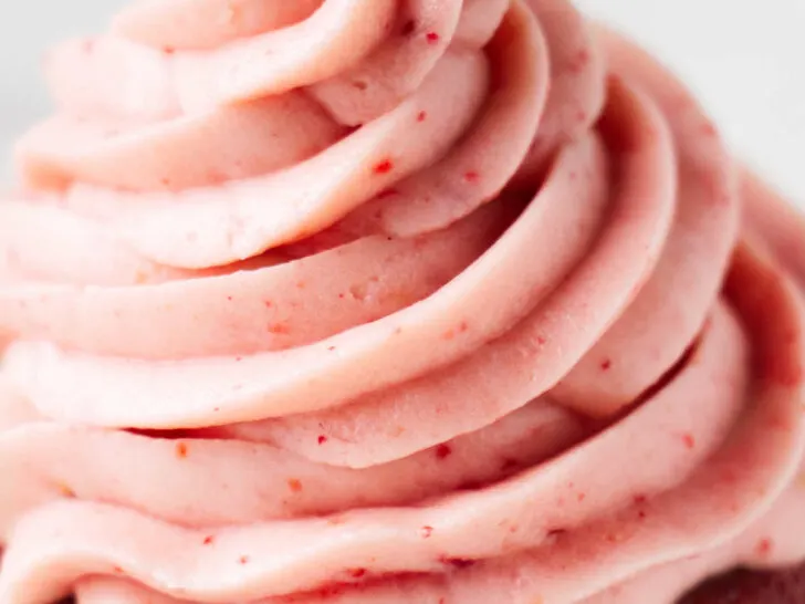 A cupcake topped with strawberry cream cheese frosting.