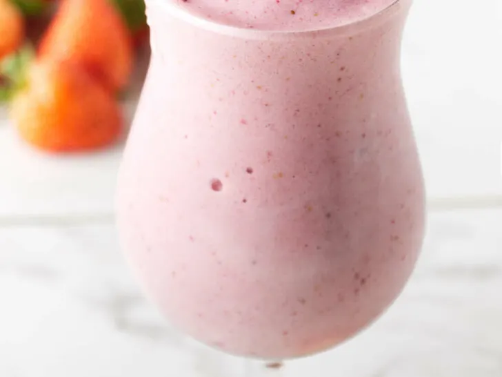 A strawberry protein shake in a tall glass.