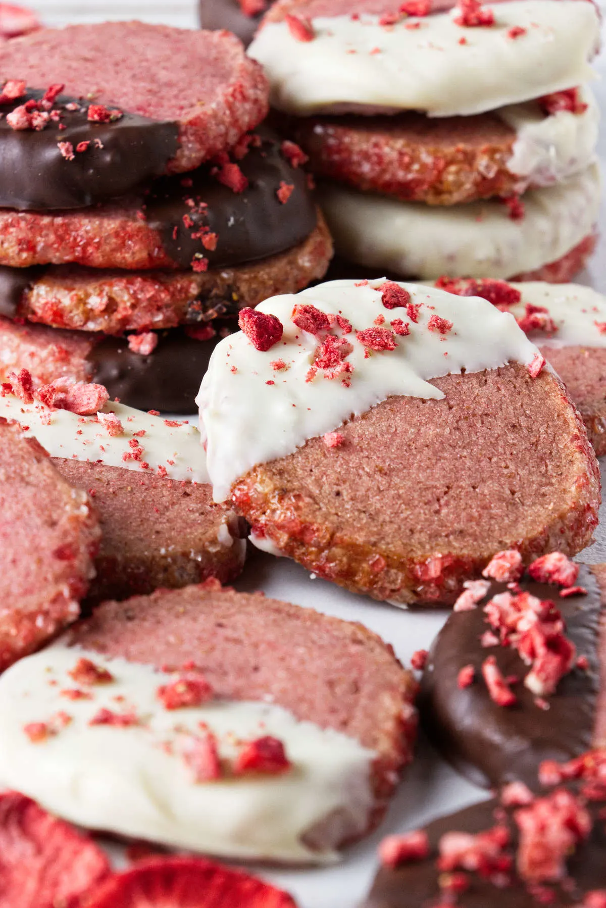 Chocolate dipped strawberry cookies with crumbled dried strawberries sprinkled on top.