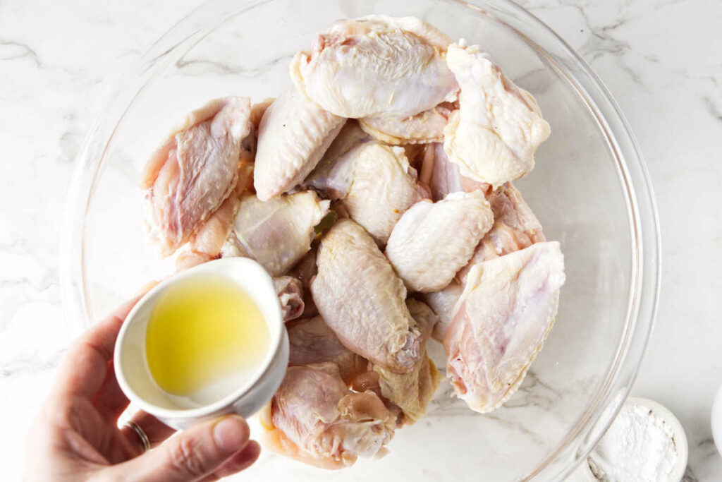 Coating chicken wings in olive oil.