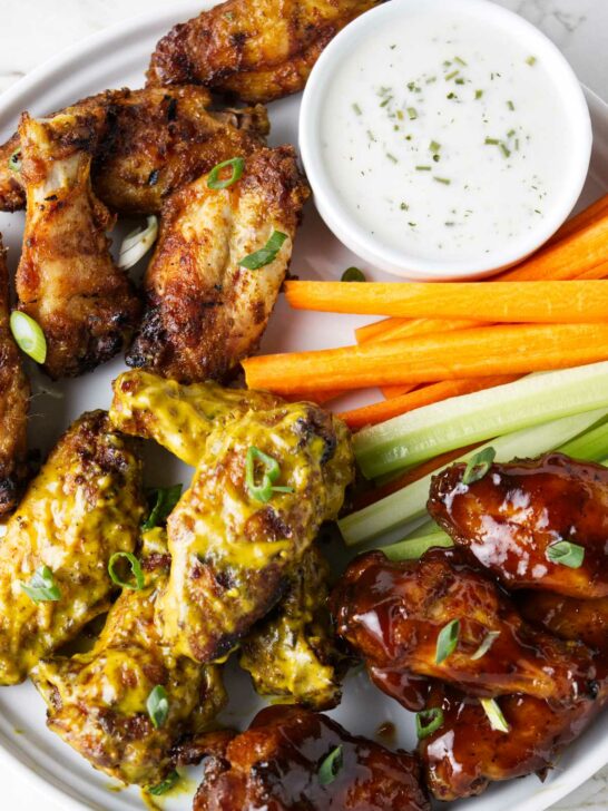 Traeger chicken wings on a serving plate with celery and carrot sticks.