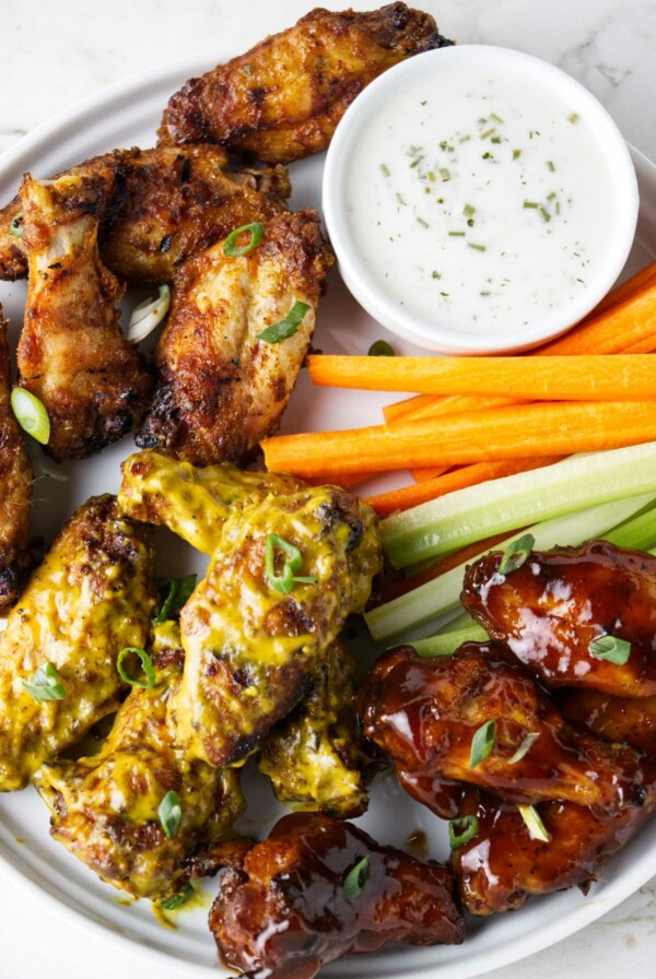 Traeger chicken wings on a serving plate with celery and carrot sticks.