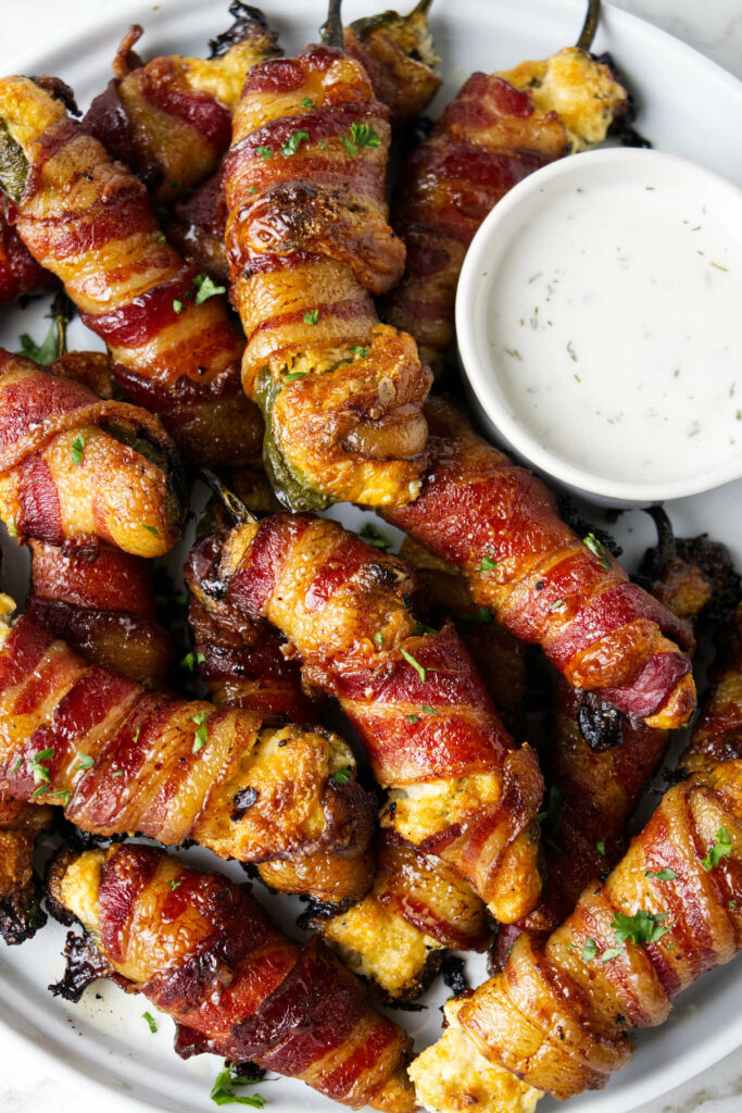 Smoked Traeger jalapeno poppers on a plate with ranch dip.