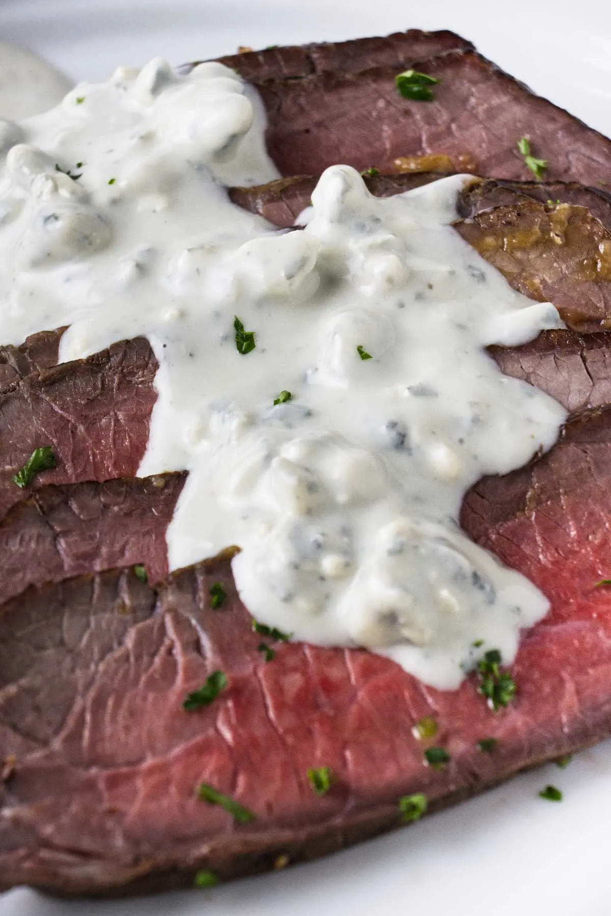 Slices of steak covered in blue cheese sauce.