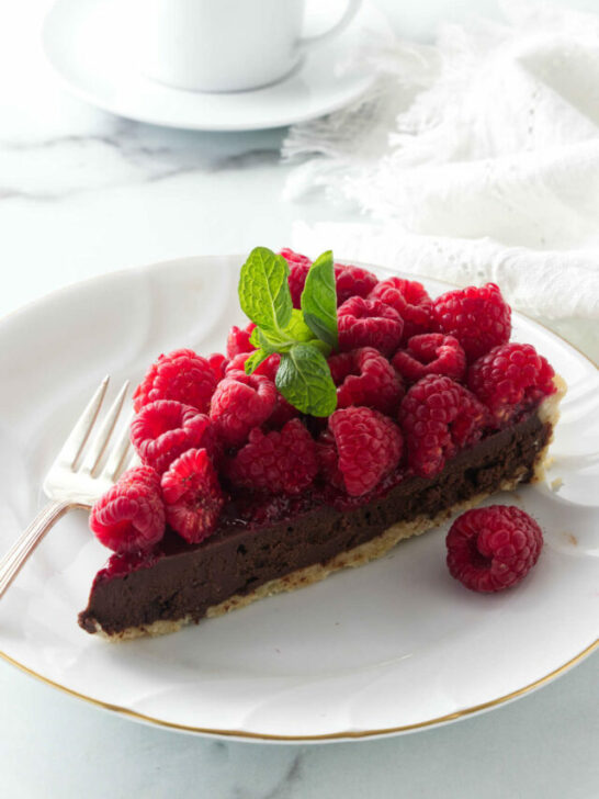 A slice of a tart on a dessert plate next to a cup of coffee.