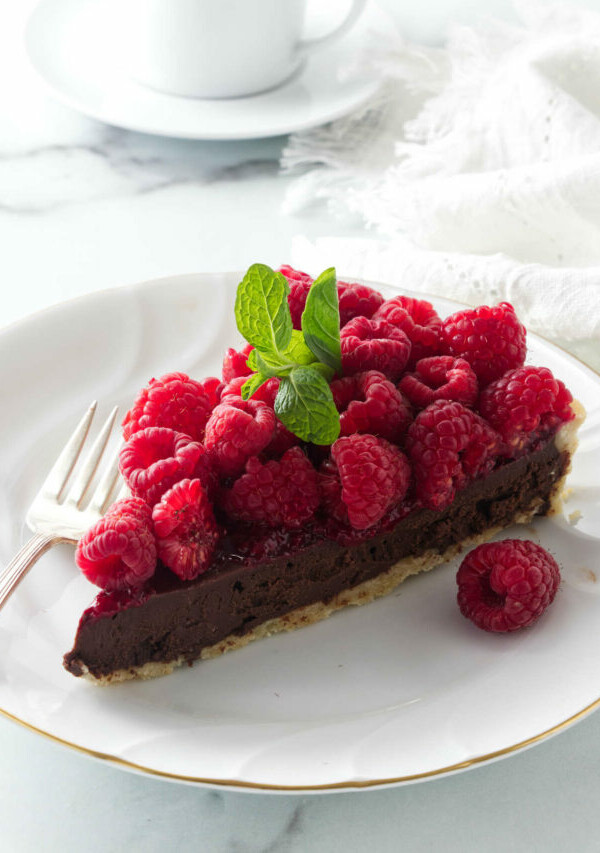 A slice of a tart on a dessert plate next to a cup of coffee.