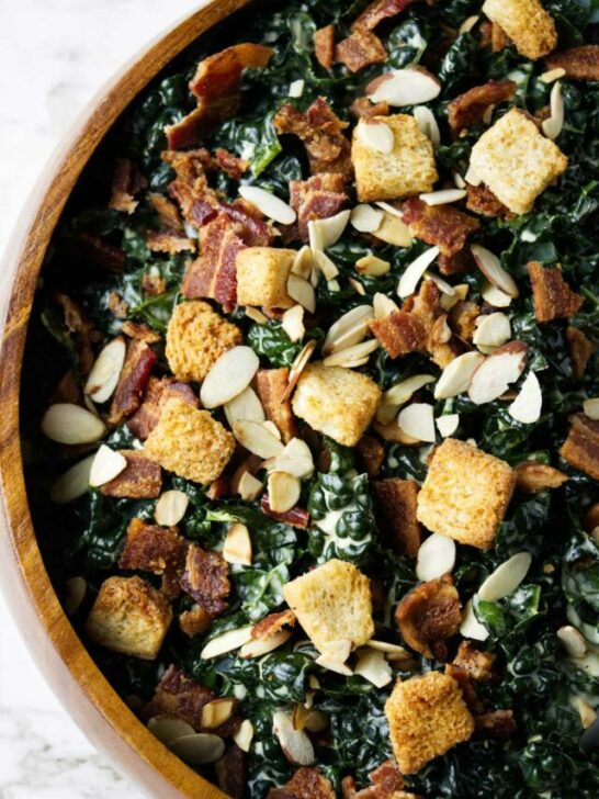 A large bowl of kale salad with croutons on top.