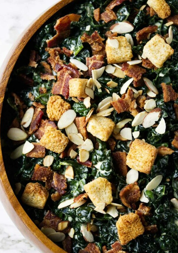 A large bowl of kale salad with croutons on top.