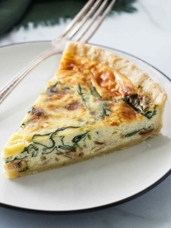 A slice of quiche with spinach baked into the center of the quiche.