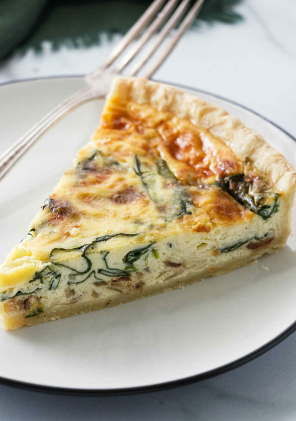 A slice of quiche with spinach baked into the center of the quiche.