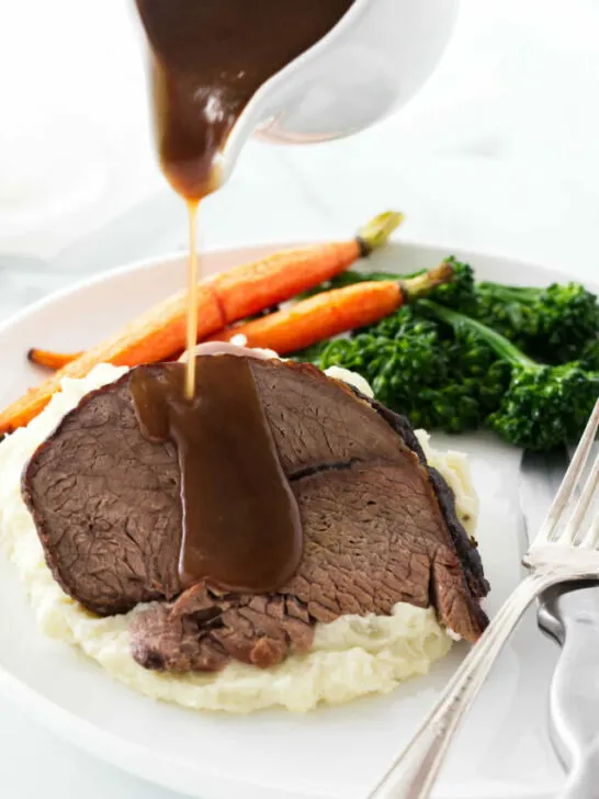 Pouring gravy over a slice of beef.