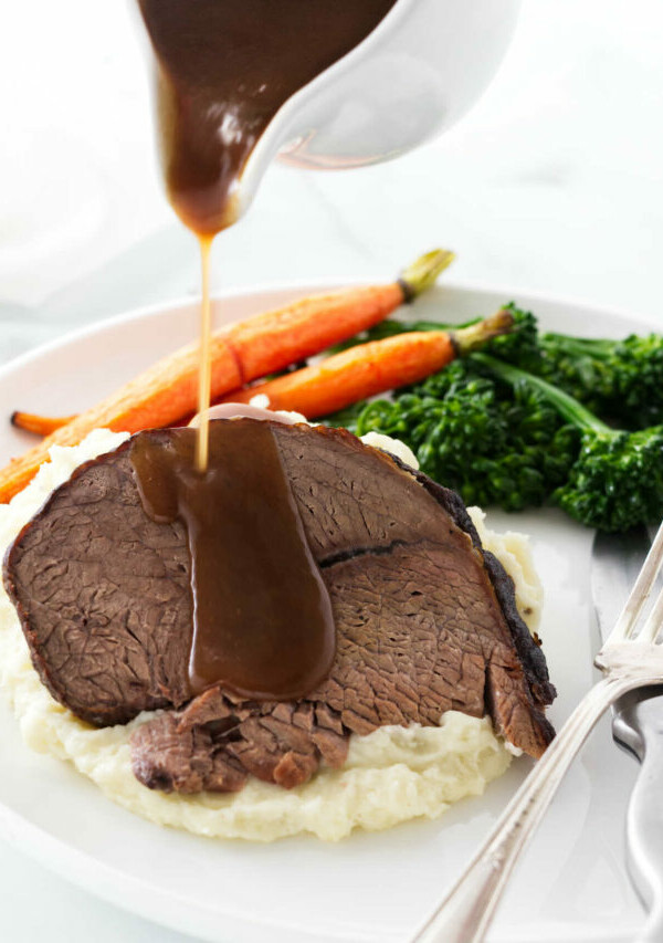 Pouring gravy over a slice of beef.