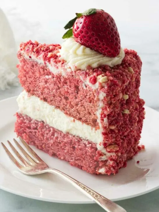 A slice of a strawberry cake coated with strawberry crunch crumble.