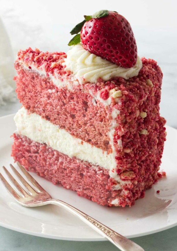 A slice of a strawberry cake coated with strawberry crunch crumble.