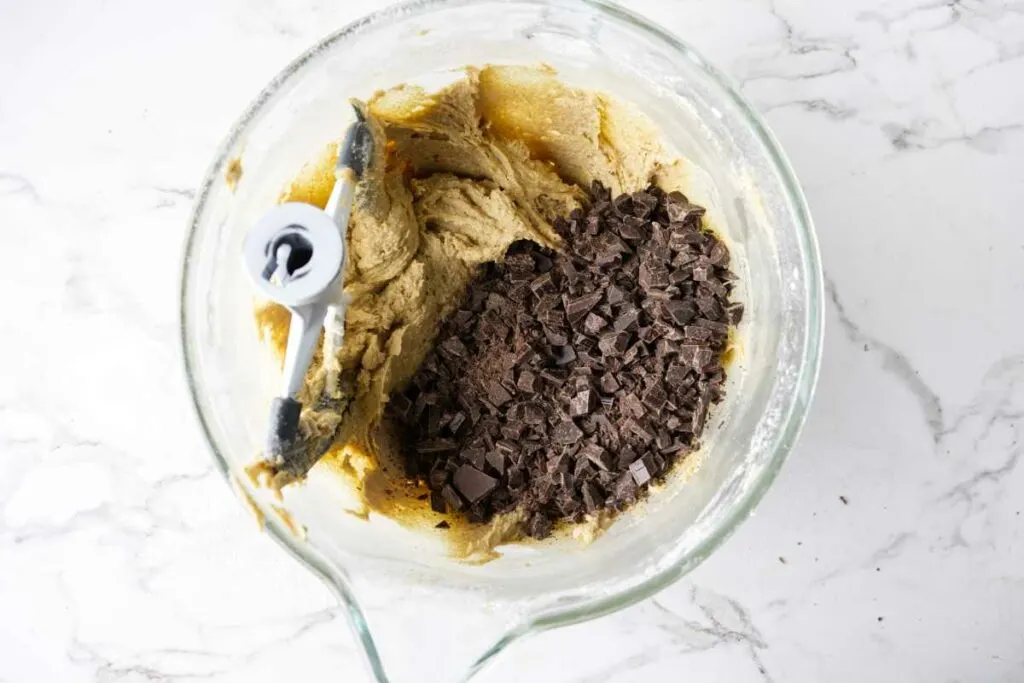 Mixing chopped chocolate into cookie batter.